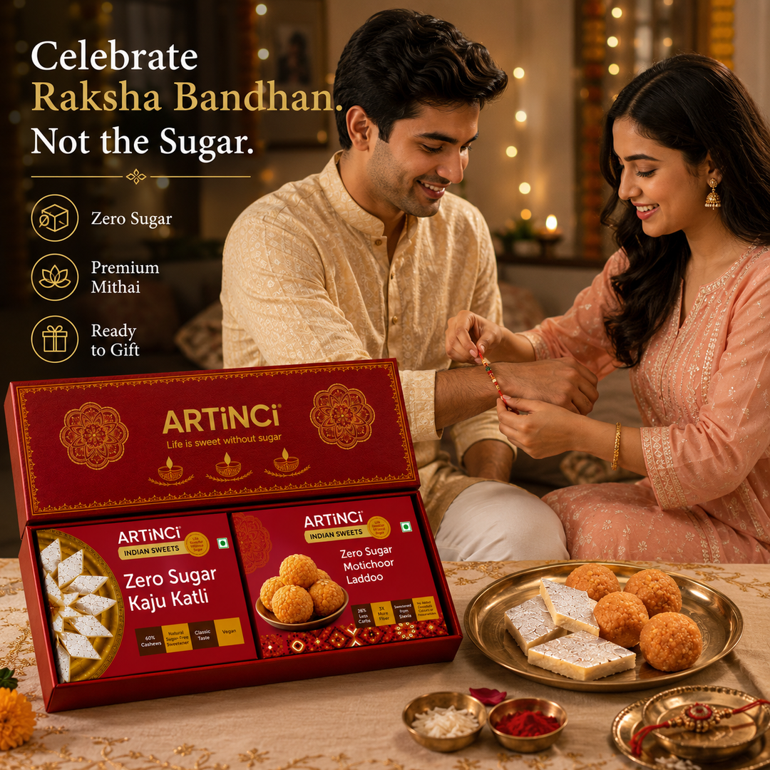 A man and woman in traditional Indian attire sit together in a warmly lit room, while an open red ARTINCI gift box of zero sugar Rajasthani laddoo and kaju kathi is displayed in the foreground with plates of sweets on a table. Text on the left reads 'Celebrate Raksha Bandhan.