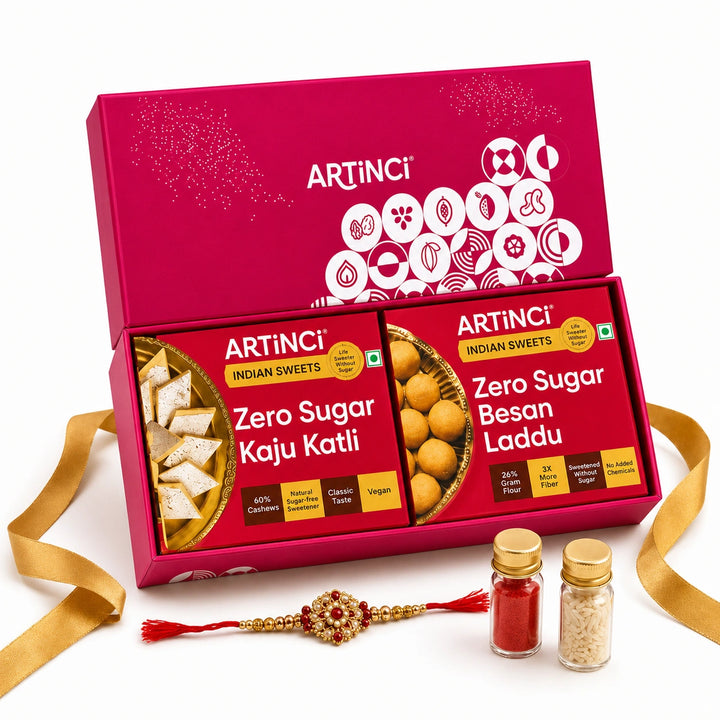 Artinci Indian Sweets gift set in a bright magenta box, featuring Zero Sugar Kaju Katli, Zero Sugar Besan Laddu, two small spice jars, and a decorative red and gold Rakhi on a white background with gold ribbon.