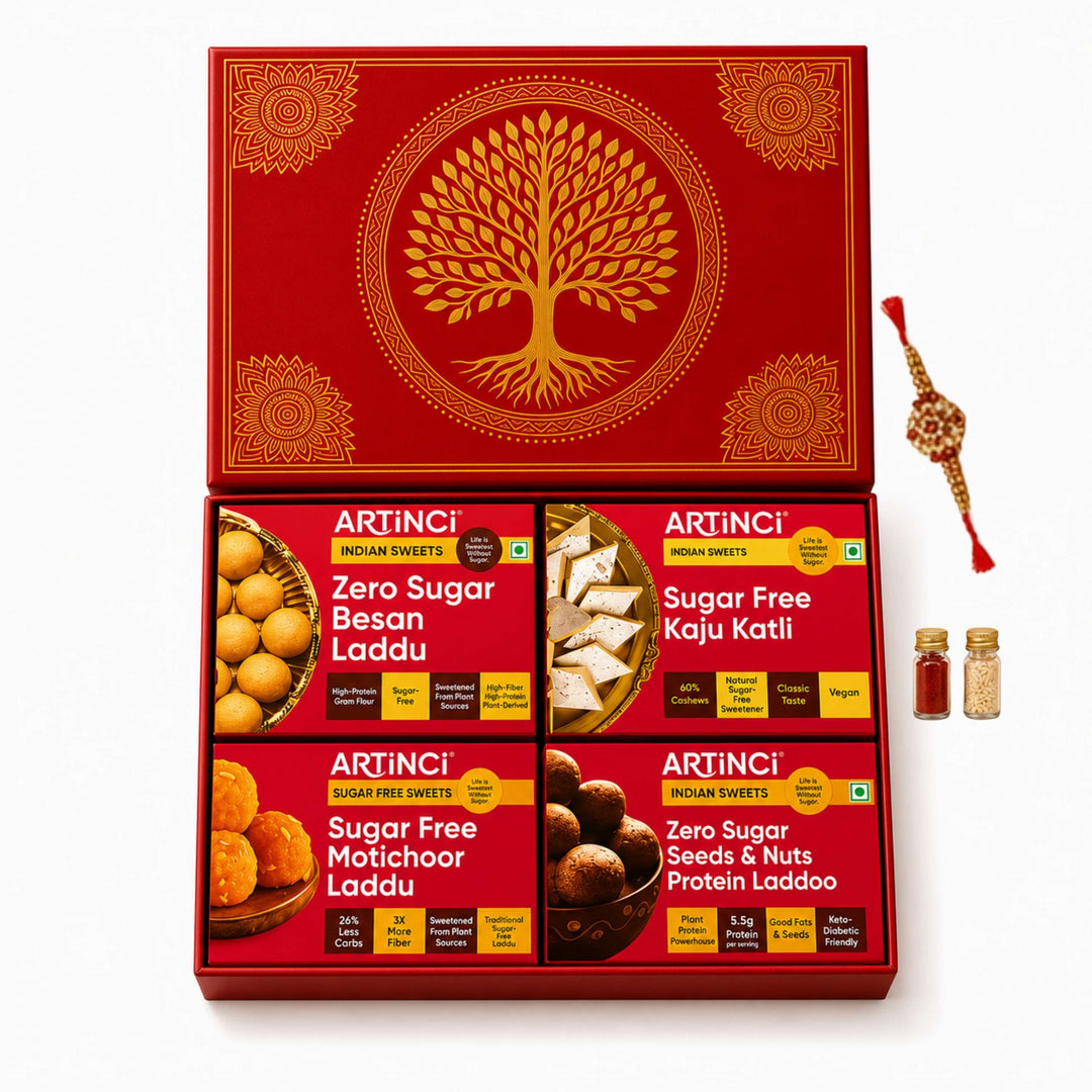 An open red ARTINCI gift box containing four varieties of sugar-free Indian sweets, shown on a clean white background with a decorative red and gold Rakhi thread bundle and two small spice jars to the right.