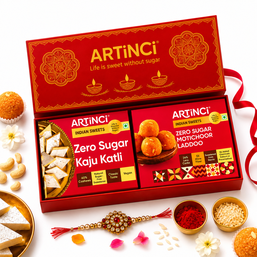ArtINCI Zero Sugar Indian Sweets gift set in a red box, displayed with surrounding festive sweets, flowers, and a Rakhi on a white background.