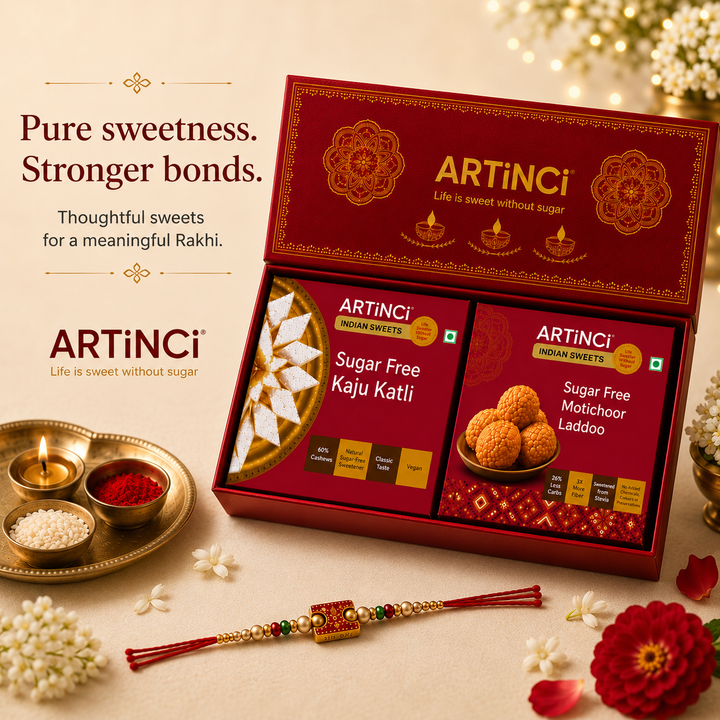ARTiNci Sweet Pack gift set displayed in an open red box with two packaged sugar-free sweets, alongside decorative Rakhi, flowers, and lit candles on a warm beige surface. Text on the left reads 'Pure sweetness.